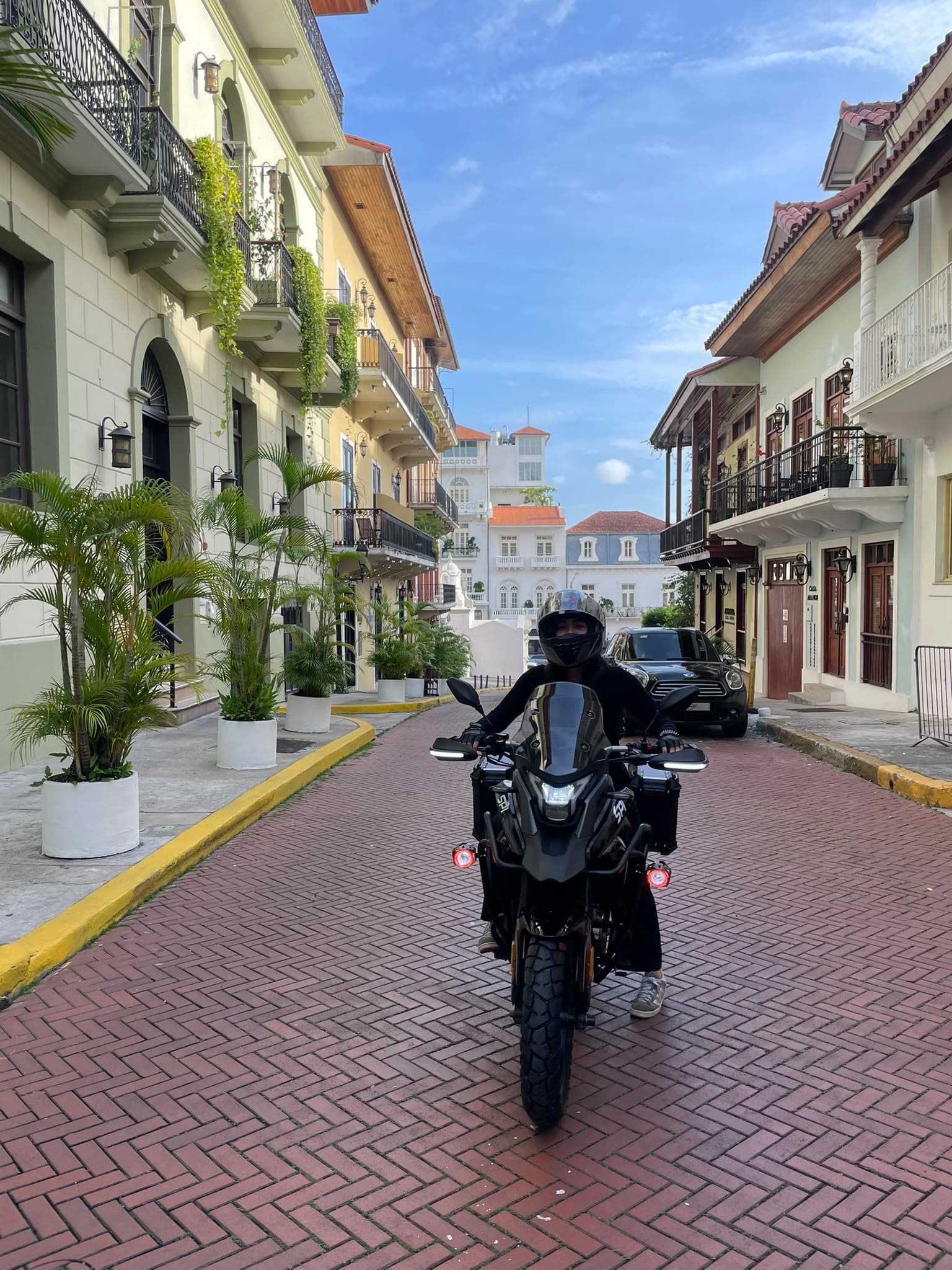 Motociclista con la SPI RX250 de XOPA Moto Rental frente a los balcones coloniales de Casco Viejo
